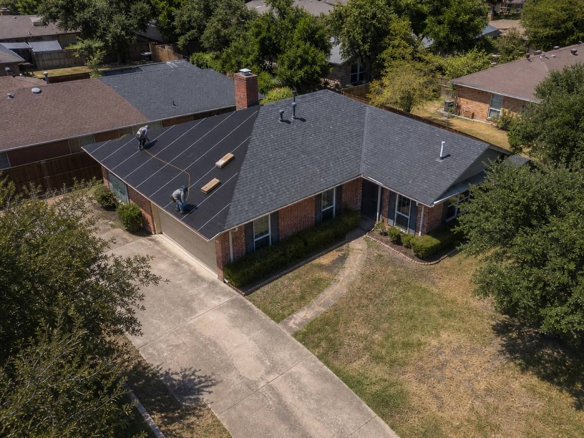 A single-storey red-brick ranch house with an L-shaped plan part-way through a architectural shingle installation, with finished and unfinished areas both visible.