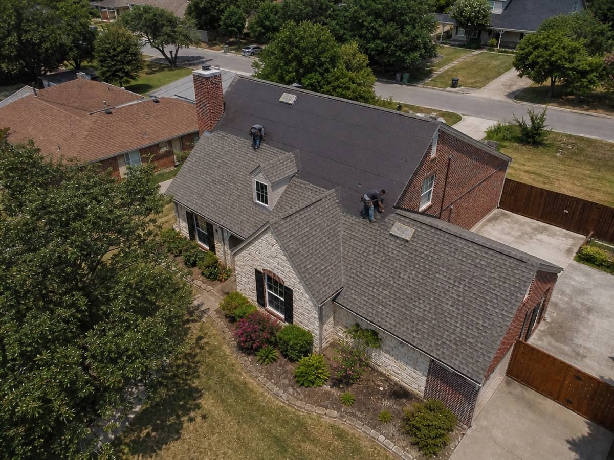 A one-and-a-half-storey house with a stone frontage and an offset garage part-way through a impact-resistant shingle installation, with finished and unfinished areas both visible.
