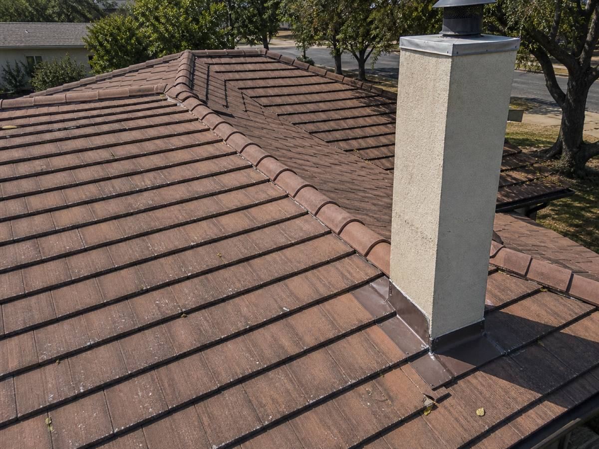 Close view of terracotta tiles running across a low hip, the weathering uneven between courses.