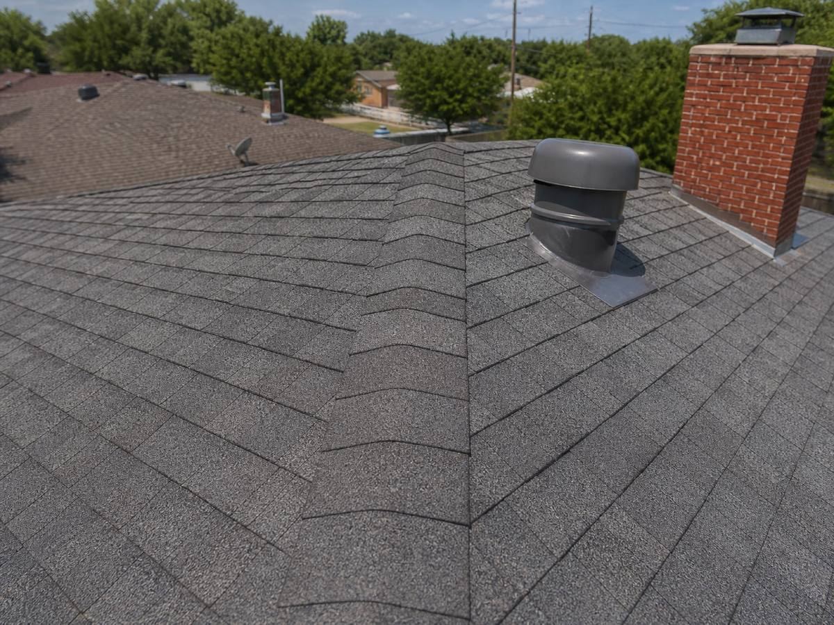 Close view of a hip meeting the eave, the shingle courses stepping down to the drip edge.