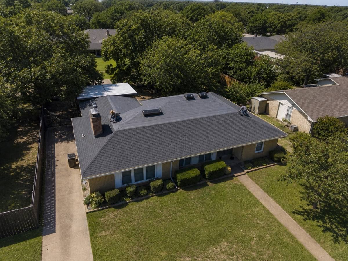 A mid-century brick ranch with two large roof planes and a rear patio cover part-way through a architectural shingle installation, with finished and unfinished areas both visible.