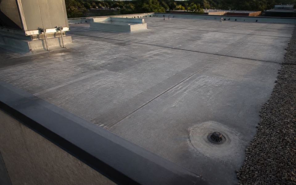 A low-slope commercial roof field with mechanical curbs, a drain and welded seam lines.